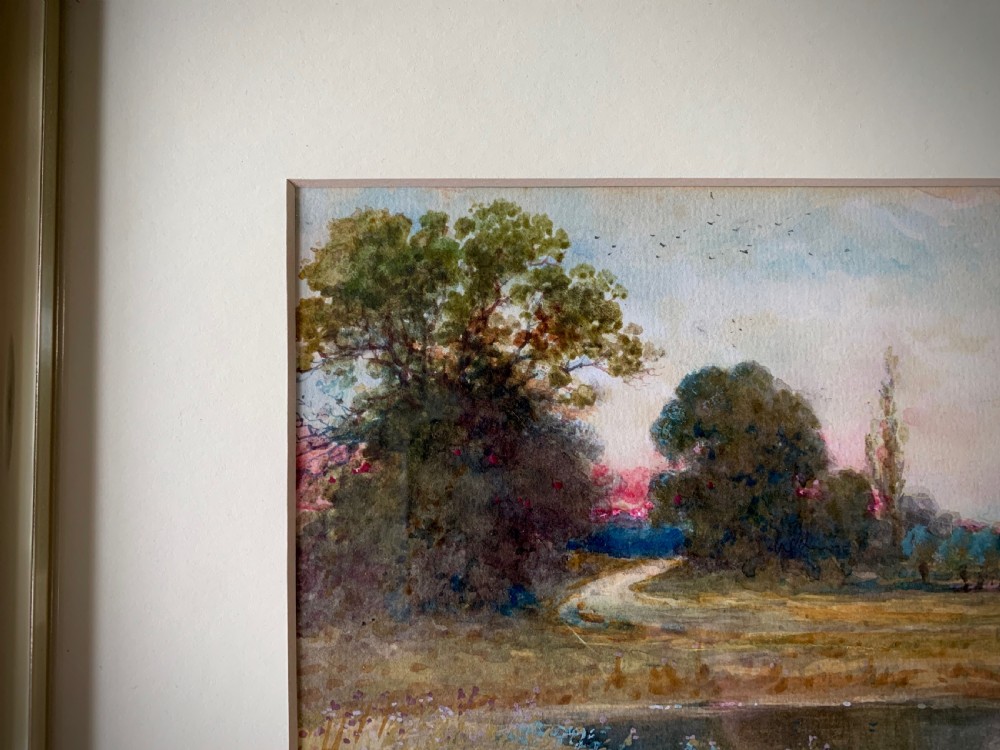 A framed 19th-century watercolour painting depicting a serene rural sunset landscape with a calm river, trees, and fields. View VIII