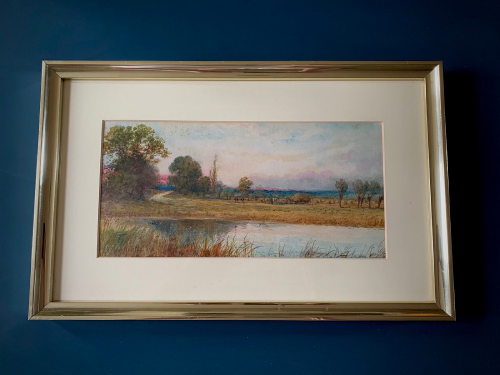A framed 19th-century watercolour painting depicting a serene rural sunset landscape with a calm river, trees, and fields. View IX
