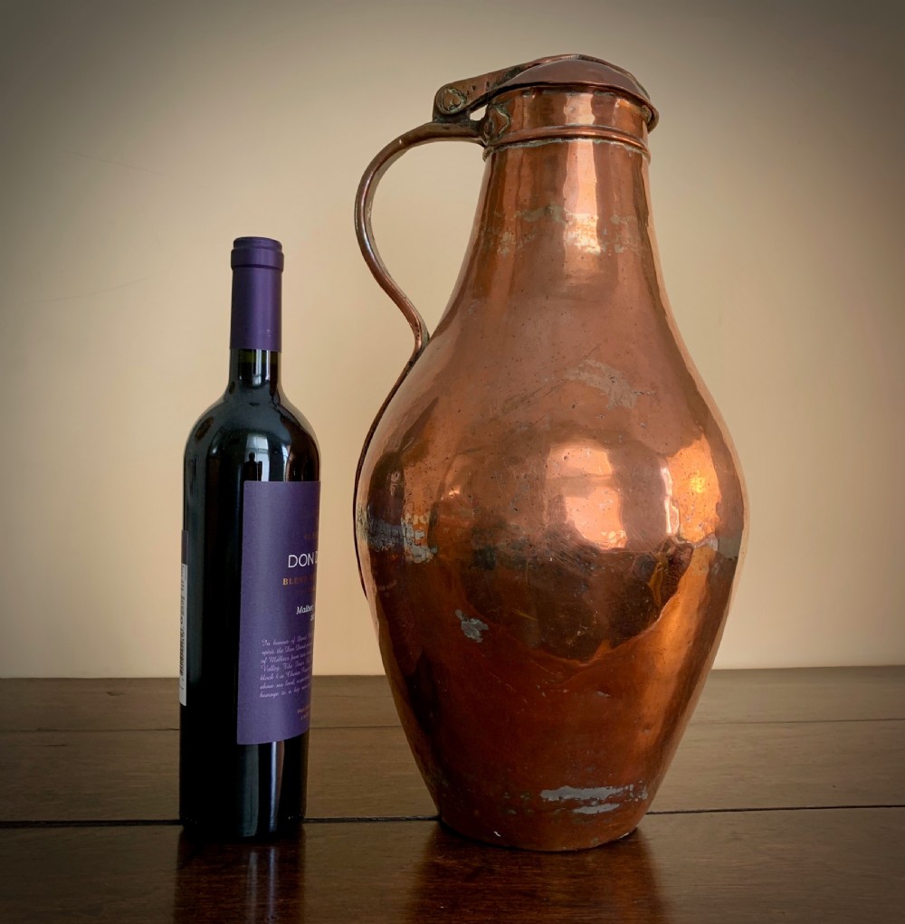A large hand-hammered copper pitcher featuring a tapered neck, rounded body, strap handle, and a hinged lid. View III