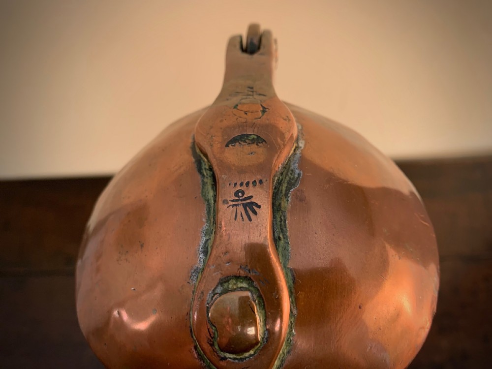 A large hand-hammered copper pitcher featuring a tapered neck, rounded body, strap handle, and a hinged lid. View VI