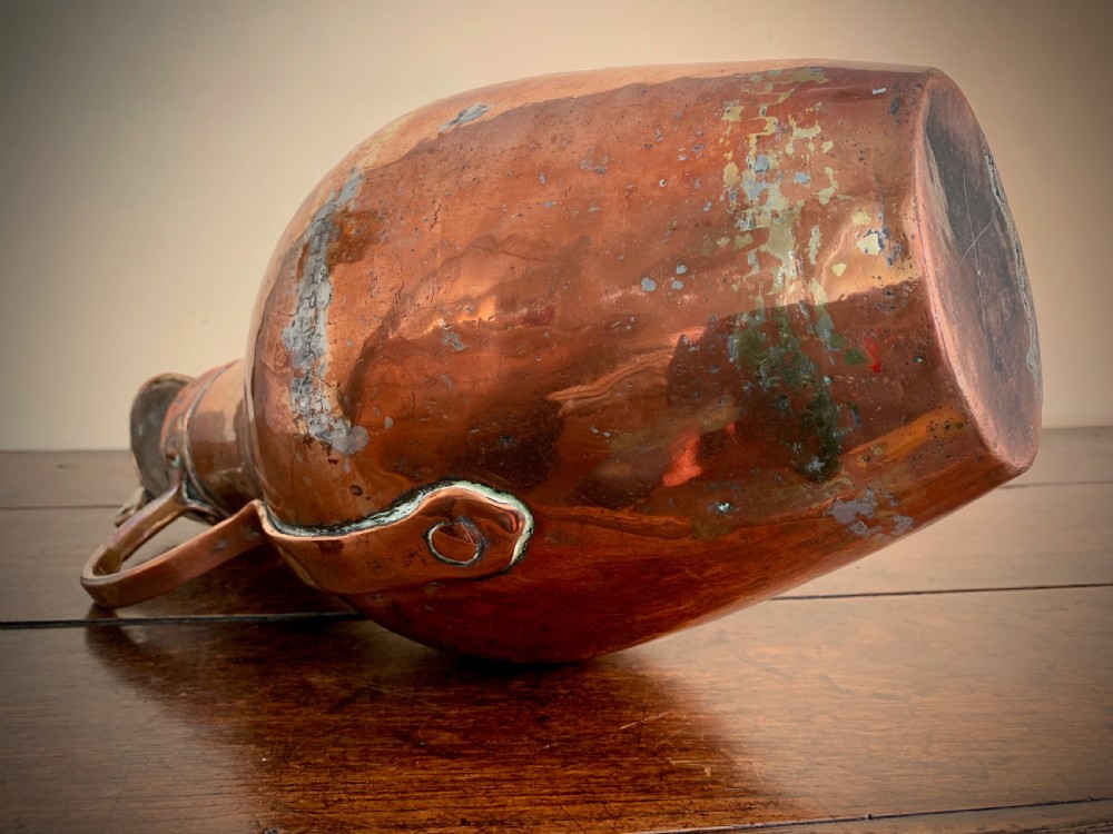 A large hand-hammered copper pitcher featuring a tapered neck, rounded body, strap handle, and a hinged lid. View VII
