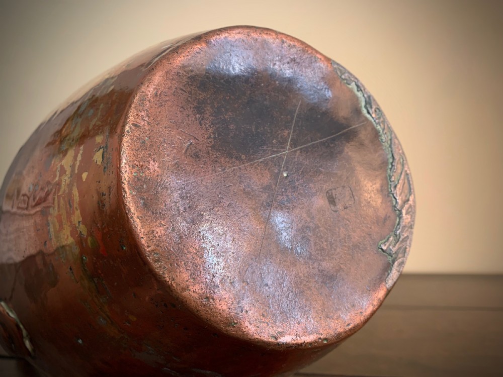 A large hand-hammered copper pitcher featuring a tapered neck, rounded body, strap handle, and a hinged lid. View VIII