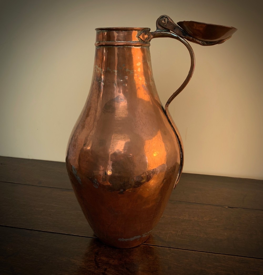 A large hand-hammered copper pitcher featuring a tapered neck, rounded body, strap handle, and a hinged lid. View X