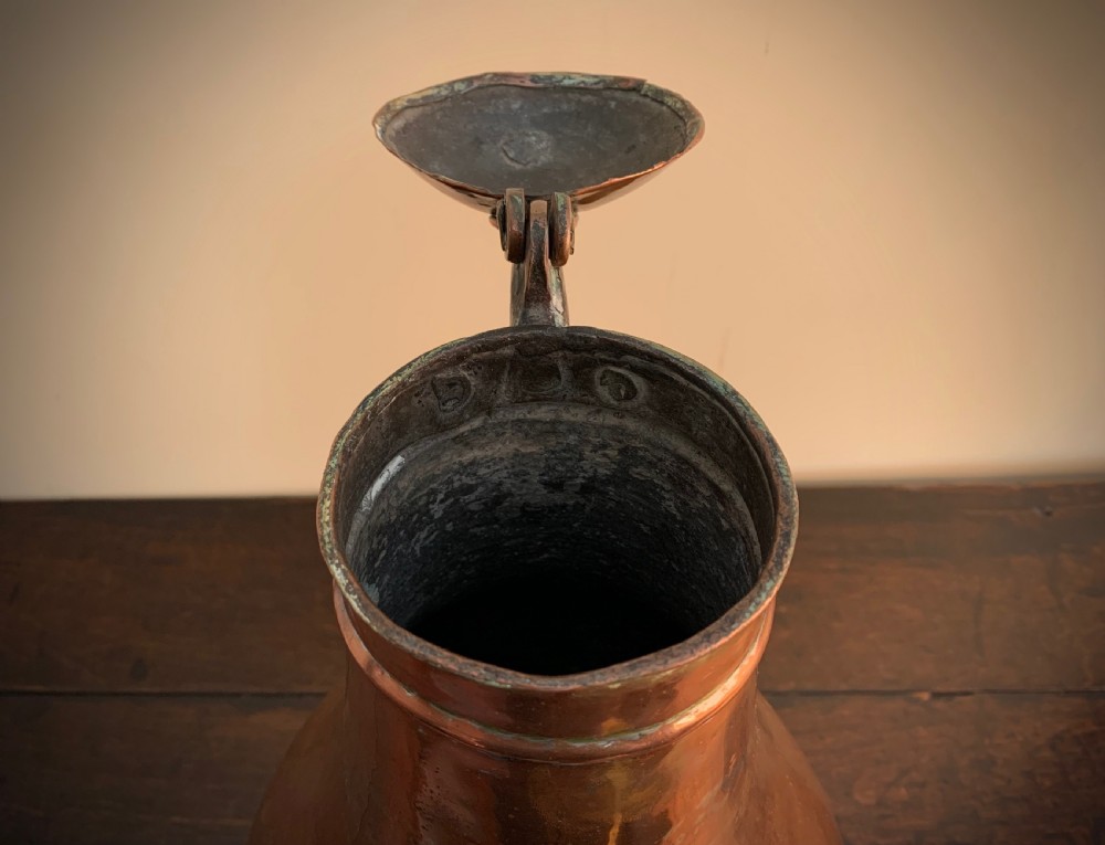 A large hand-hammered copper pitcher featuring a tapered neck, rounded body, strap handle, and a hinged lid. View XII
