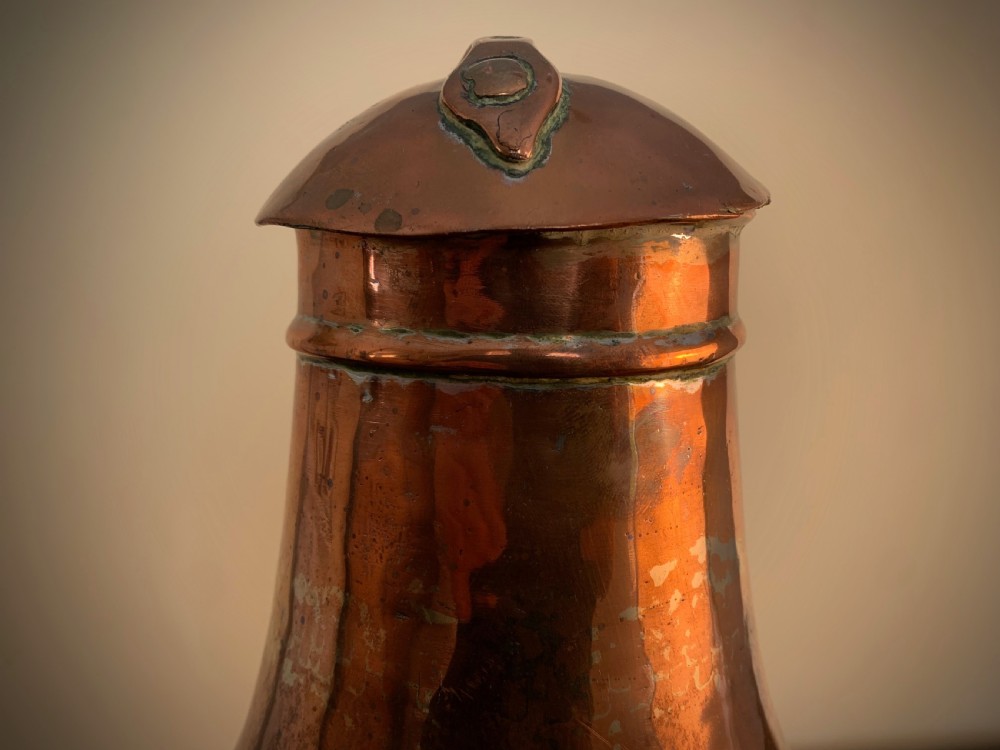 A large hand-hammered copper pitcher featuring a tapered neck, rounded body, strap handle, and a hinged lid. View XIII