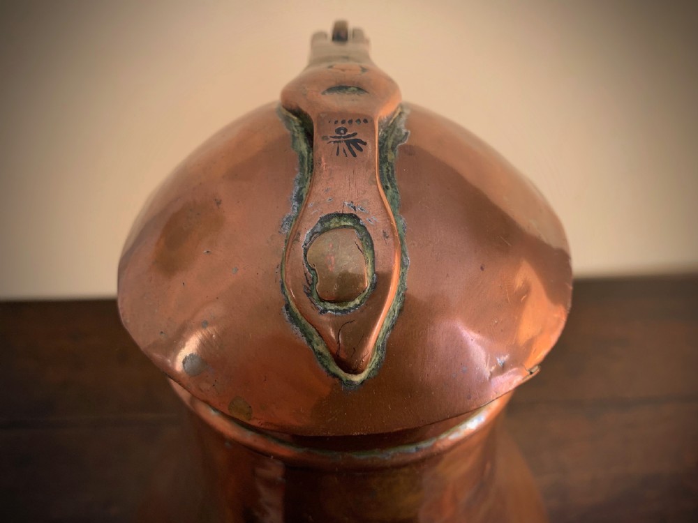 A large hand-hammered copper pitcher featuring a tapered neck, rounded body, strap handle, and a hinged lid. View XV