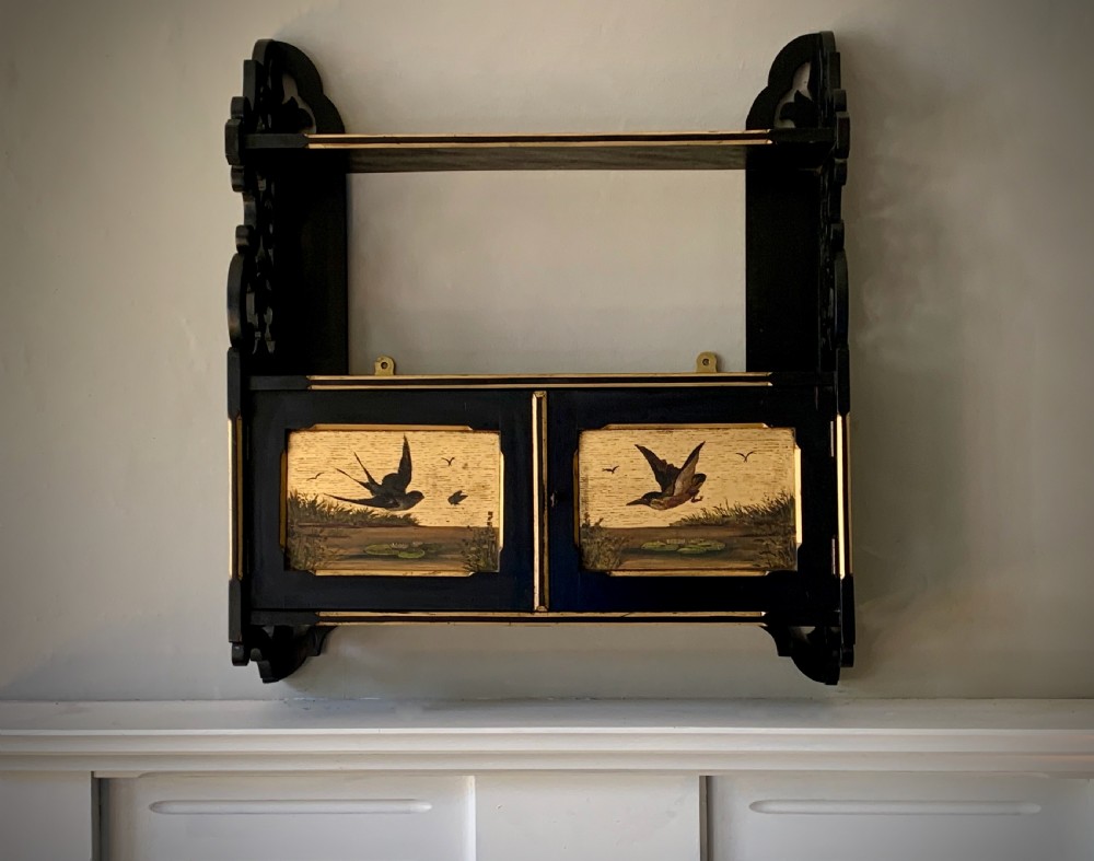 AESTHETIC MOVEMENT EBONISED WALL CABINET WITH GILDED PANELS PAINTED WITH BIRDS.
