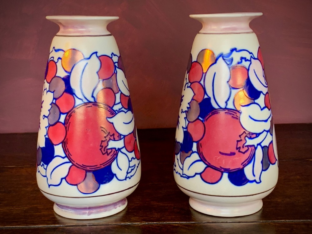 A pair of Art Deco earthenware vases featuring tubelined fruit motifs with iridescent lustre glazing on a cream background. View VI