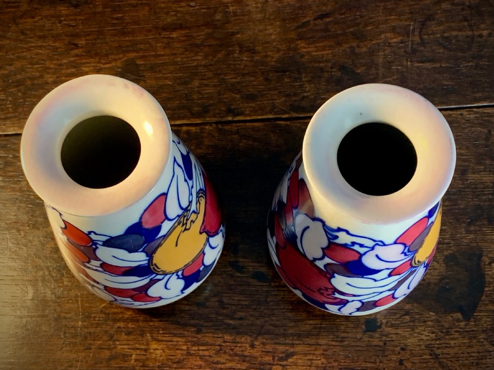 A pair of Art Deco earthenware vases featuring tubelined fruit motifs with iridescent lustre glazing on a cream background. View VII