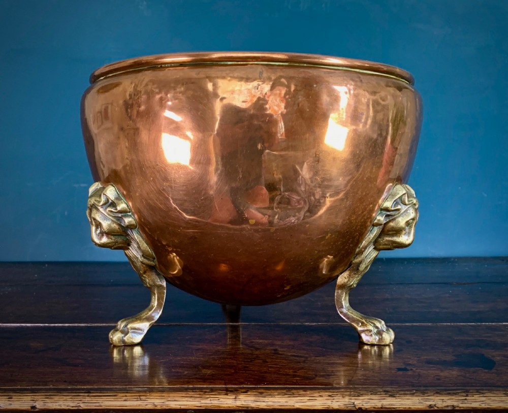 A rounded nineteenth-century copper jardiniere bowl supported on three cast brass lion mask paw feet. View II