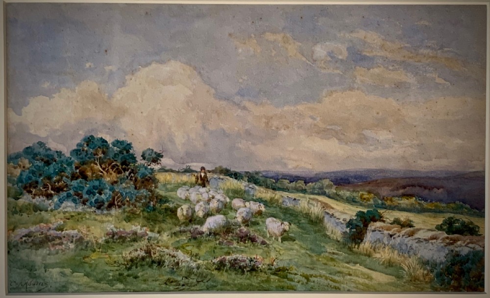 An antique framed watercolour painting depicting a shepherd driving sheep across a green moorland beneath a cloudy sky, set within a cream mount and gold frame. View II