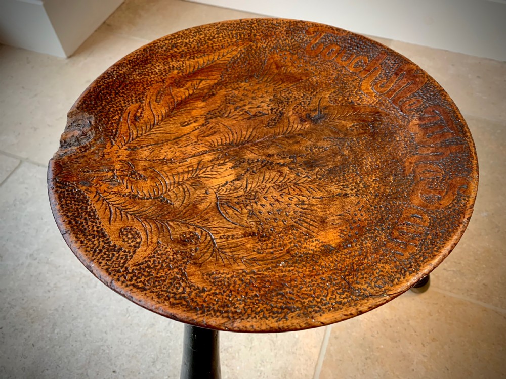 A 19th-century Scottish tripod stool crafted from dark brown wood with a circular seat featuring burnt pokerwork text and a Scottish thistle motif. View II