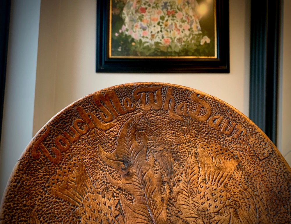 A 19th-century Scottish tripod stool crafted from dark brown wood with a circular seat featuring burnt pokerwork text and a Scottish thistle motif. View IV