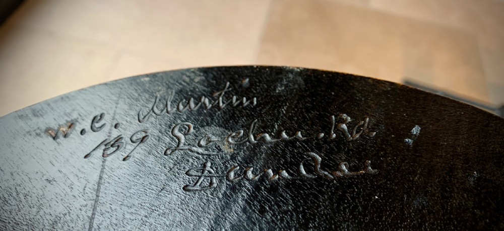 A 19th-century Scottish tripod stool crafted from dark brown wood with a circular seat featuring burnt pokerwork text and a Scottish thistle motif. View VII