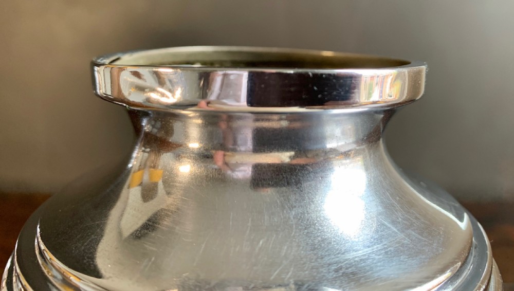 A pair of Art Deco chrome-plated metal vases with hammered lower bodies, geometric moulding near the rim, and circular stepped bases. View X