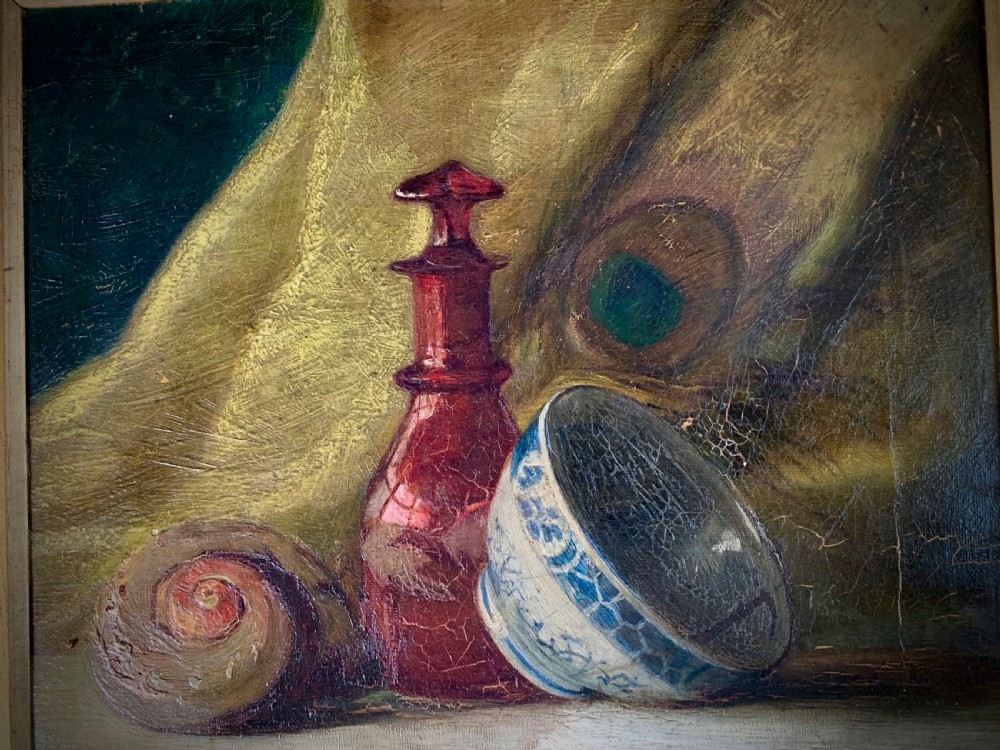 A 19th-century framed oil painting depicting a seashell, a red glass bottle, and a porcelain bowl set against draped fabric. View V