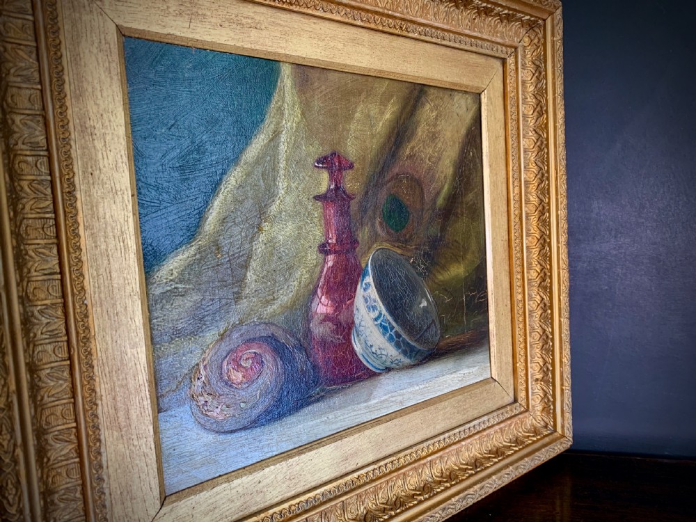 A 19th-century framed oil painting depicting a seashell, a red glass bottle, and a porcelain bowl set against draped fabric. View XIII