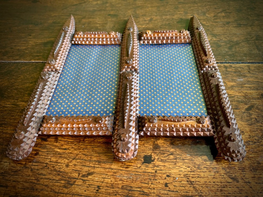 An antique tramp art double picture frame made of carved wood with layered notched geometric borders. View V