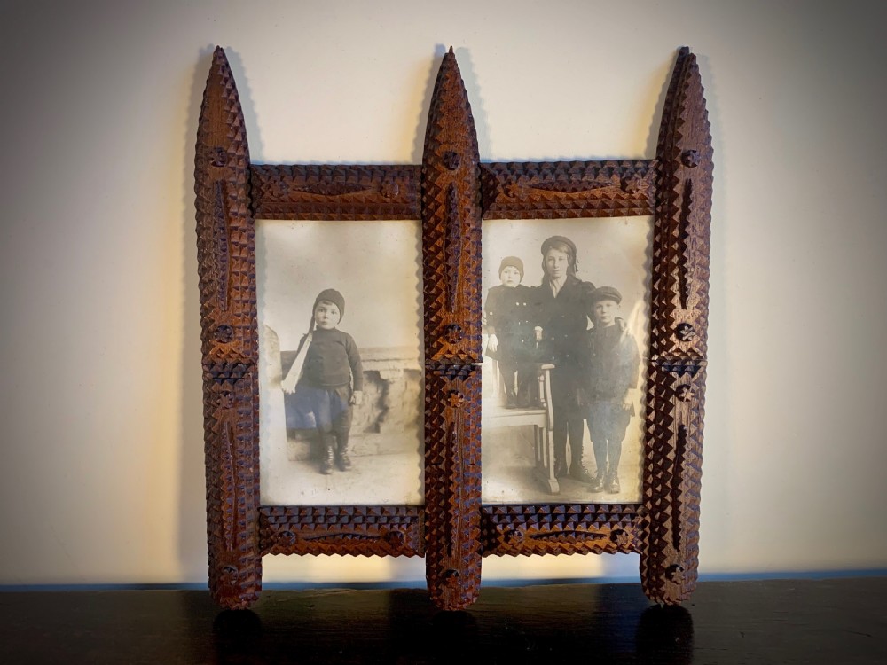 An antique tramp art double picture frame made of carved wood with layered notched geometric borders. View VII
