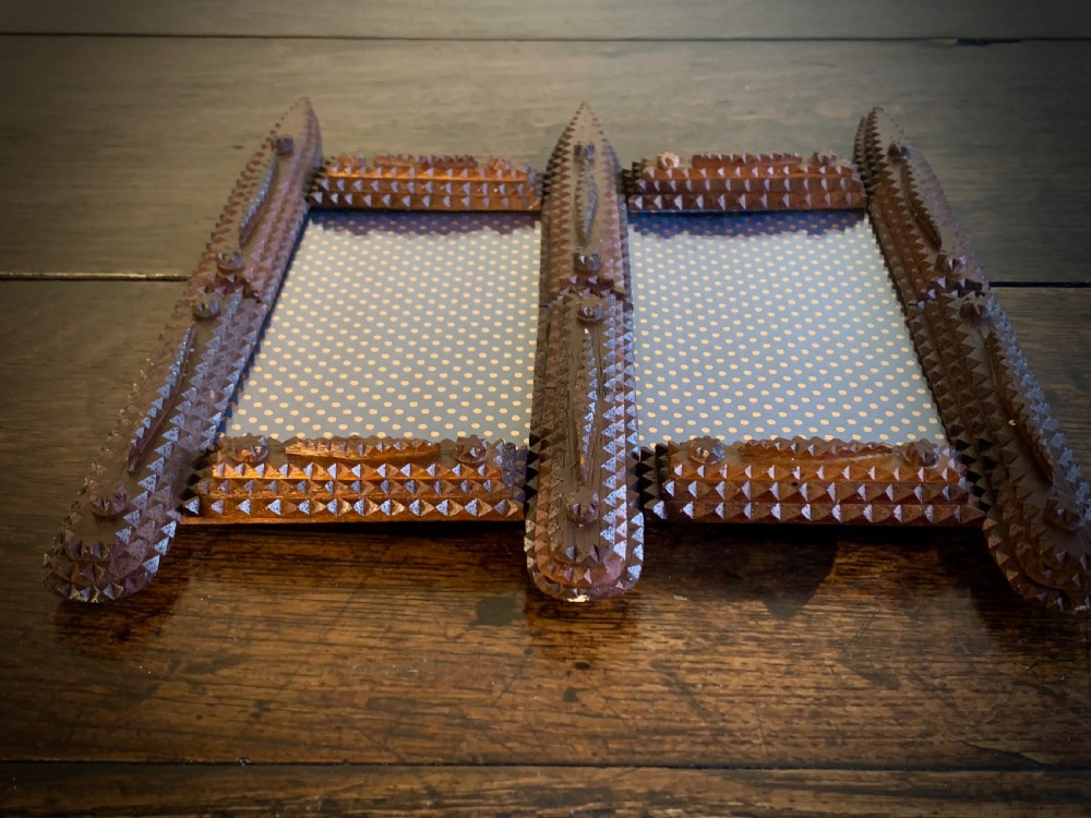 An antique tramp art double picture frame made of carved wood with layered notched geometric borders. View IX