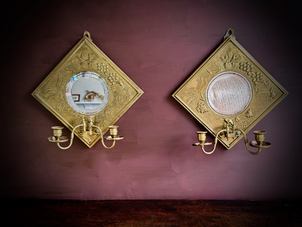 A pair of diamond-shaped embossed brass girandole wall mirrors featuring Chinoiserie scenes and twin candle branches. View II