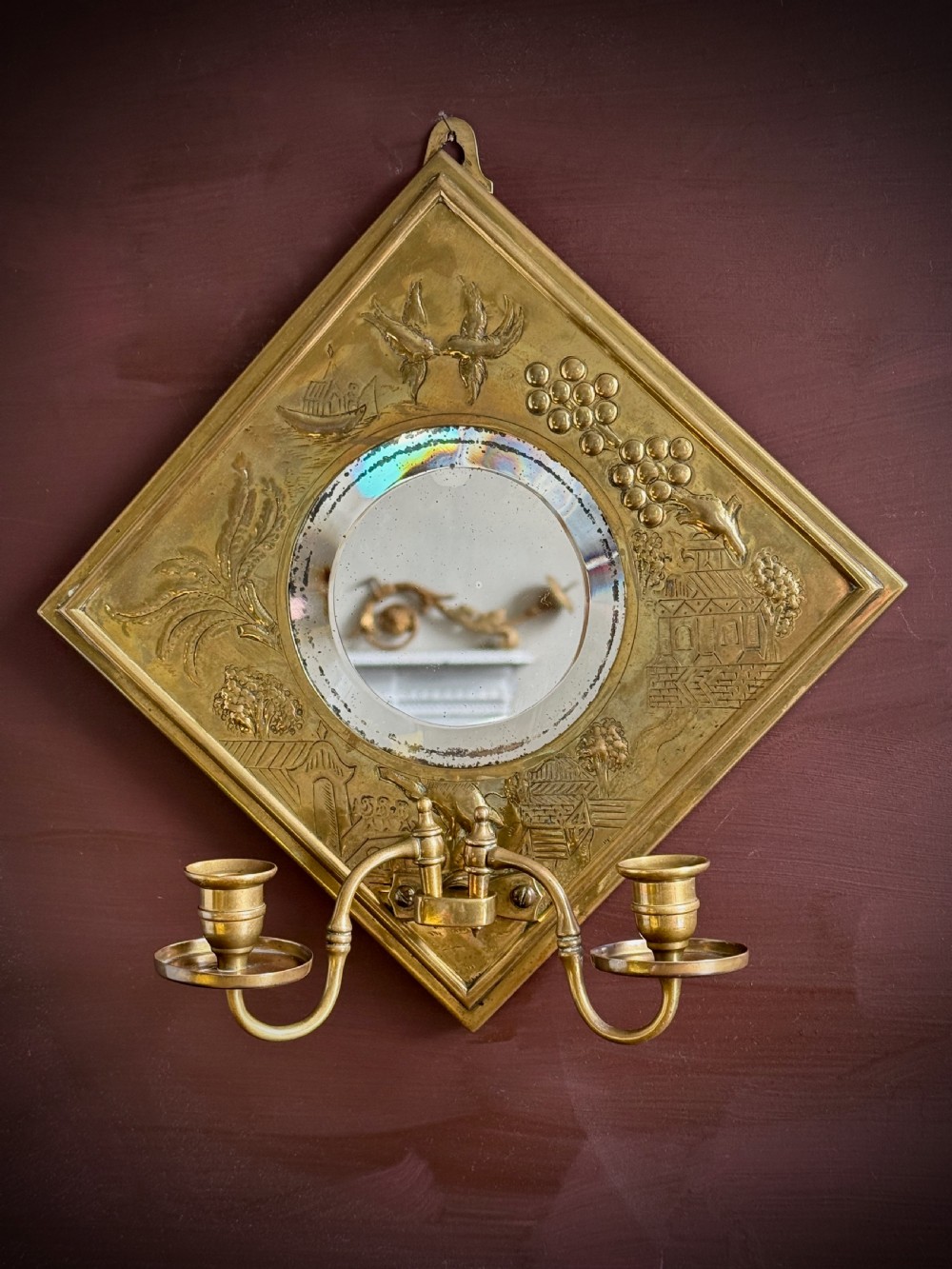 A pair of diamond-shaped embossed brass girandole wall mirrors featuring Chinoiserie scenes and twin candle branches. View XII
