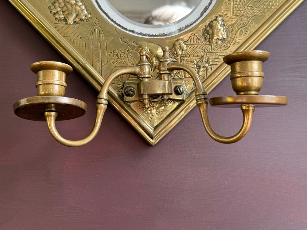 A pair of diamond-shaped embossed brass girandole wall mirrors featuring Chinoiserie scenes and twin candle branches. View XV