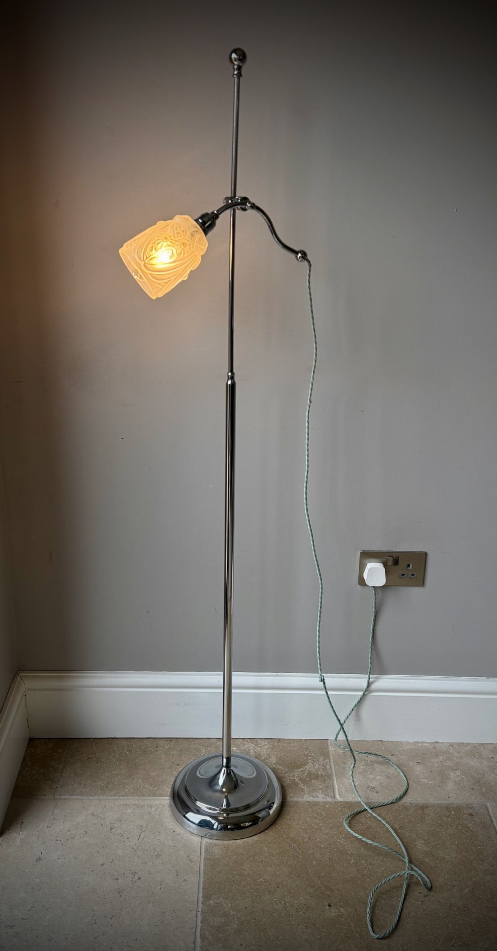 A slender 1920s Art Deco adjustable floor lamp crafted from polished chrome with an articulated neck and a lit frosted glass shade. View II