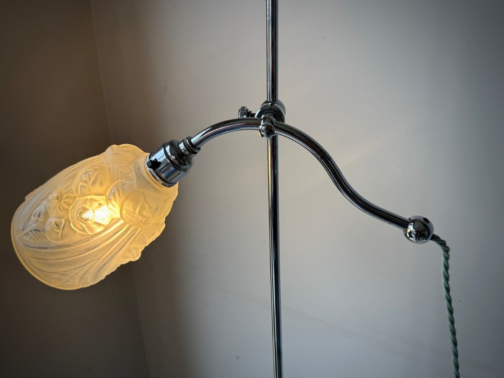 A slender 1920s Art Deco adjustable floor lamp crafted from polished chrome with an articulated neck and a lit frosted glass shade. View III