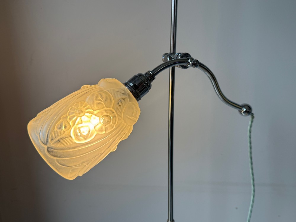 A slender 1920s Art Deco adjustable floor lamp crafted from polished chrome with an articulated neck and a lit frosted glass shade. View V