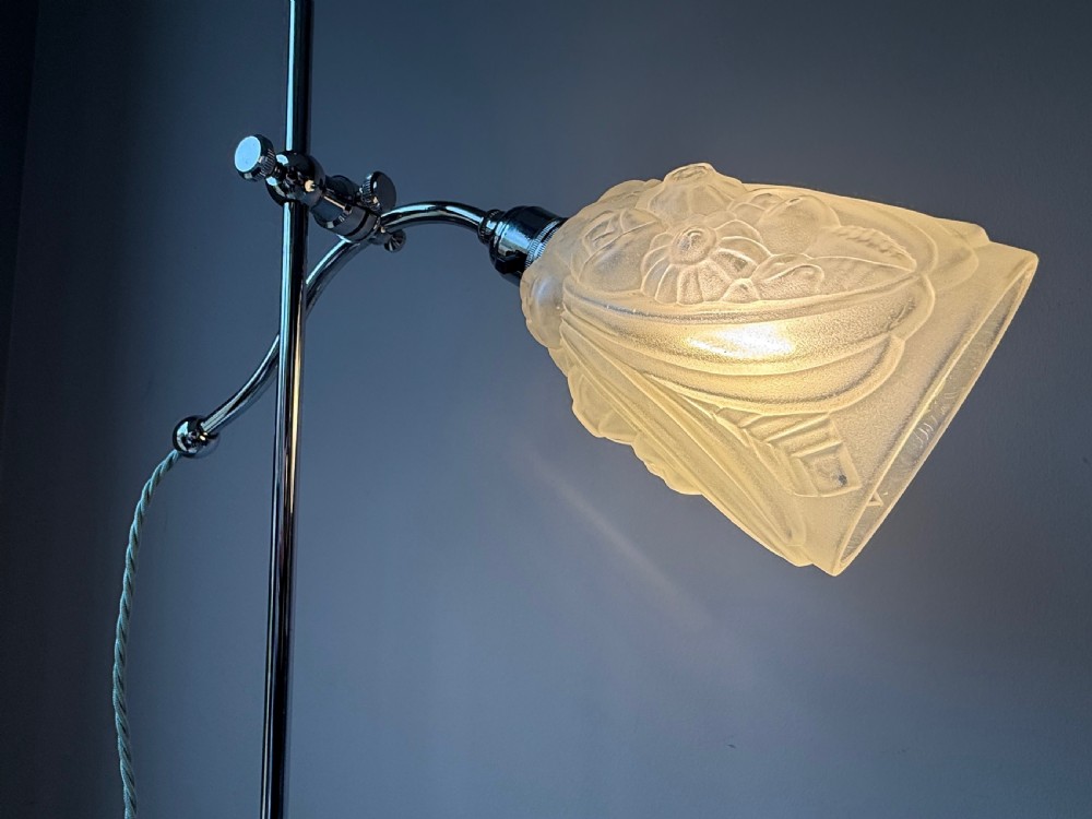 A slender 1920s Art Deco adjustable floor lamp crafted from polished chrome with an articulated neck and a lit frosted glass shade. View XX
