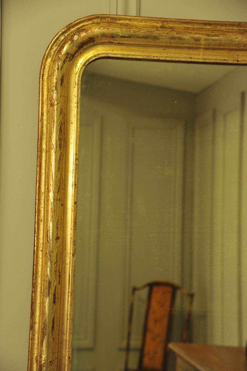 A large 19th-century French wall mirror featuring a gilded gesso frame with rounded top corners and aged patina. View III