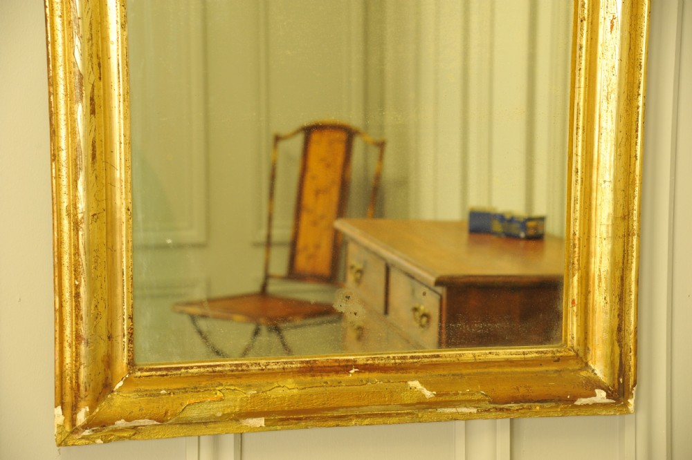A large 19th-century French wall mirror featuring a gilded gesso frame with rounded top corners and aged patina. View V