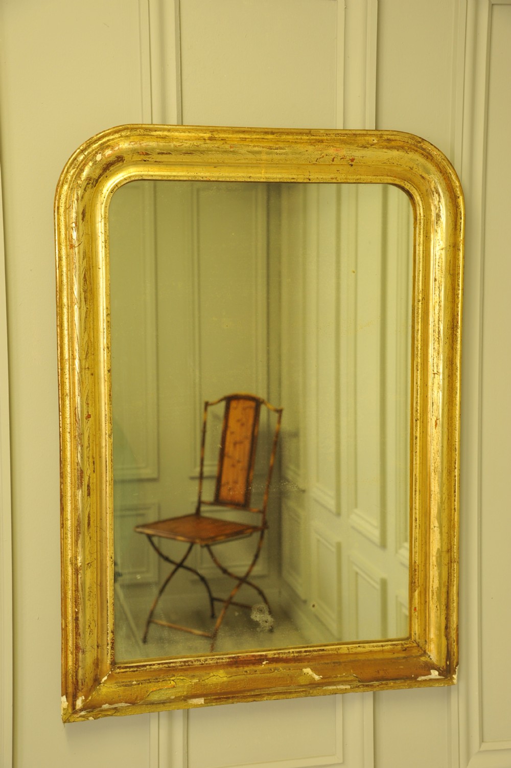 A large 19th-century French wall mirror featuring a gilded gesso frame with rounded top corners and aged patina. View VII