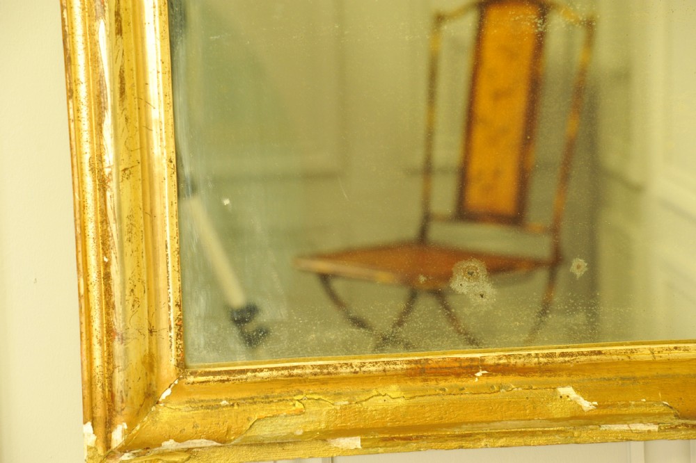 A large 19th-century French wall mirror featuring a gilded gesso frame with rounded top corners and aged patina. View X