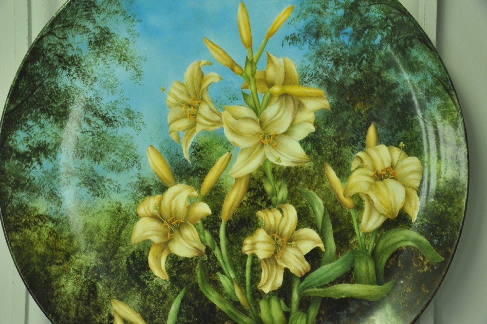 A circular hand-painted porcelain decorative plate displaying yellow lilies against foliage and a blue sky. View II