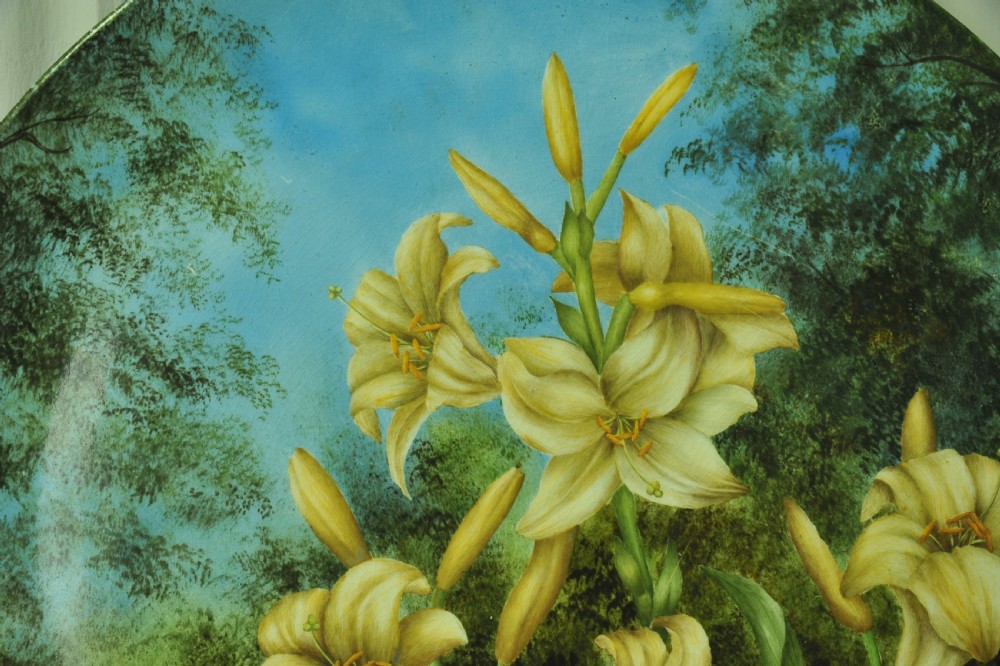 A circular hand-painted porcelain decorative plate displaying yellow lilies against foliage and a blue sky. View V