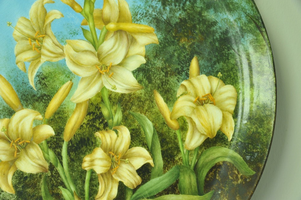 A circular hand-painted porcelain decorative plate displaying yellow lilies against foliage and a blue sky. View VII