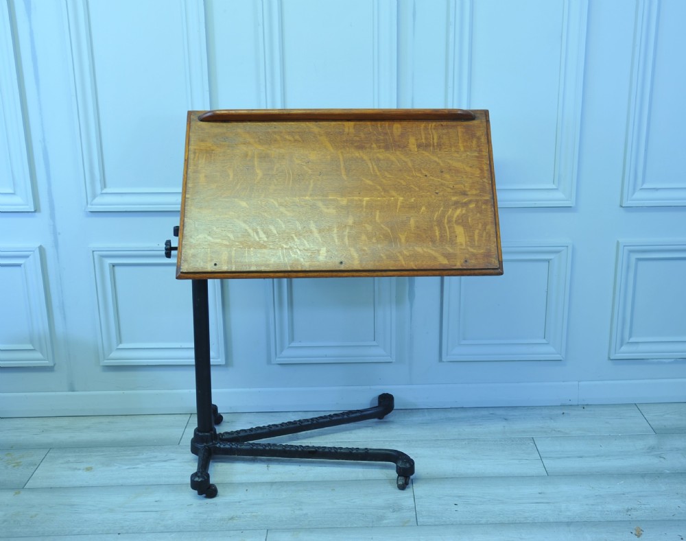 An antique adjustable oak top reading table mounted on a black cast iron pedestal base with castors. View IV