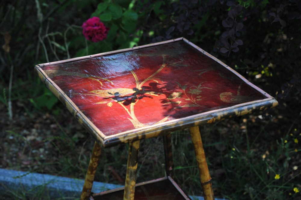 A two-tier bamboo side table featuring a square red lacquered top and lower shelf decorated with gilded bird and botanical motifs. View II