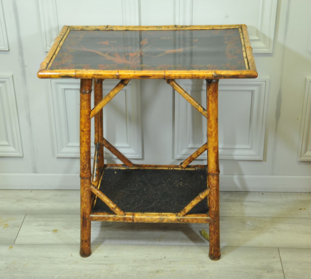 A late Victorian two-tier bamboo side table featuring a dark lacquered top panel decorated with botanical flora and birds. View II