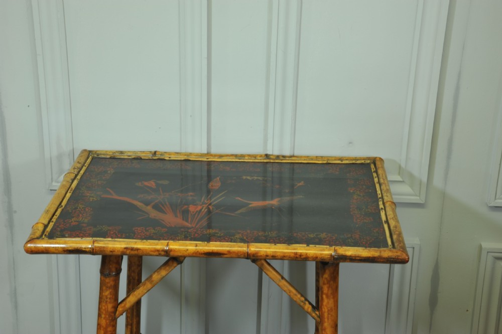 A late Victorian two-tier bamboo side table featuring a dark lacquered top panel decorated with botanical flora and birds. View IV