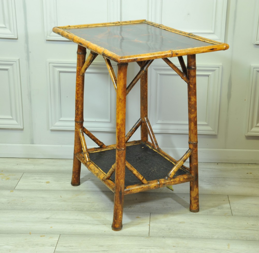A late Victorian two-tier bamboo side table featuring a dark lacquered top panel decorated with botanical flora and birds. View VI