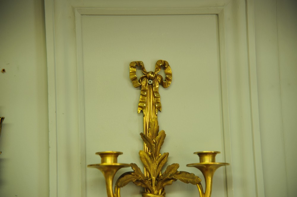 A pair of nineteenth-century French gilt bronze wall sconces featuring ribbon bow tops, tassel drops, and two curved candle branches. View VII