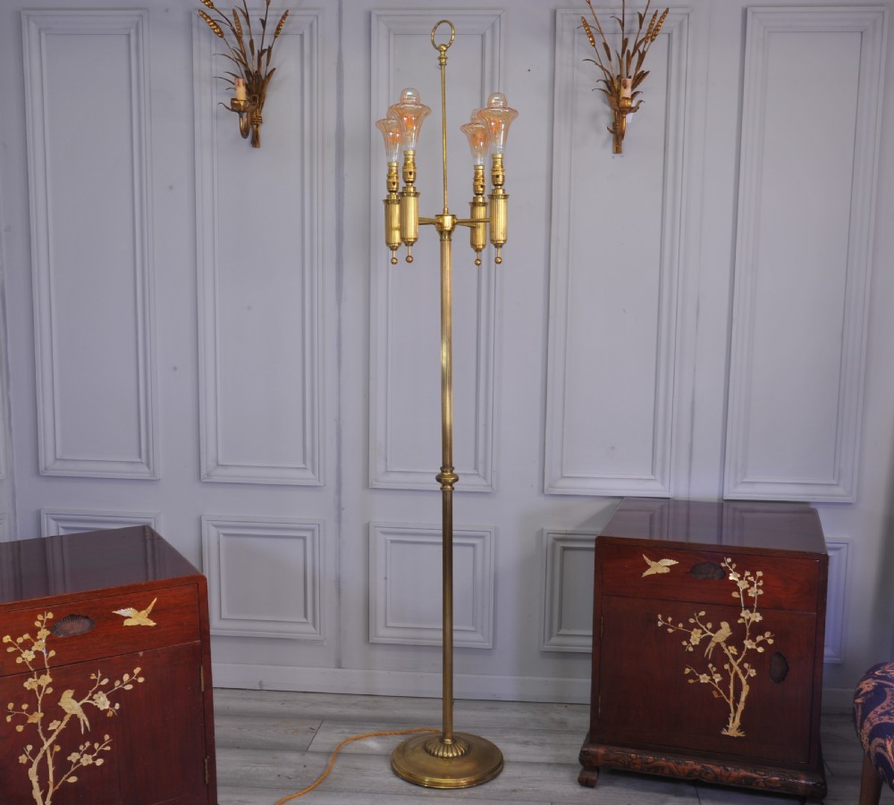 A brass French bouillotte style standard lamp featuring four fluted candle sockets with tulip glass shades and a central ring finial.