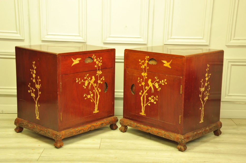 A pair of reddish-brown wood side cabinets featuring hand-painted gilt Chinoiserie floral and bird motifs resting on carved plinths. View II