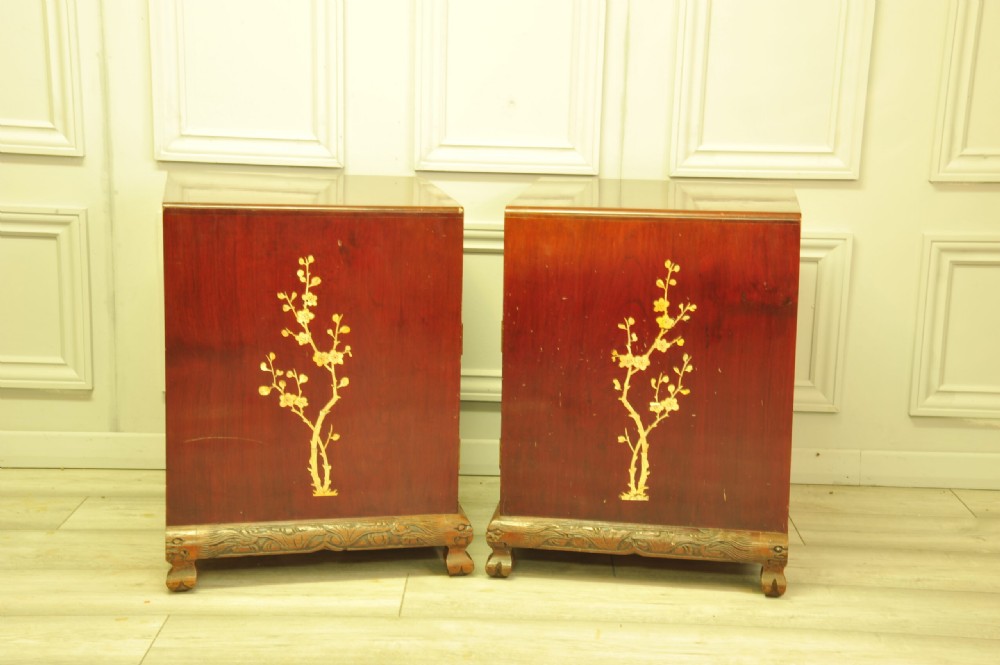 A pair of reddish-brown wood side cabinets featuring hand-painted gilt Chinoiserie floral and bird motifs resting on carved plinths. View V