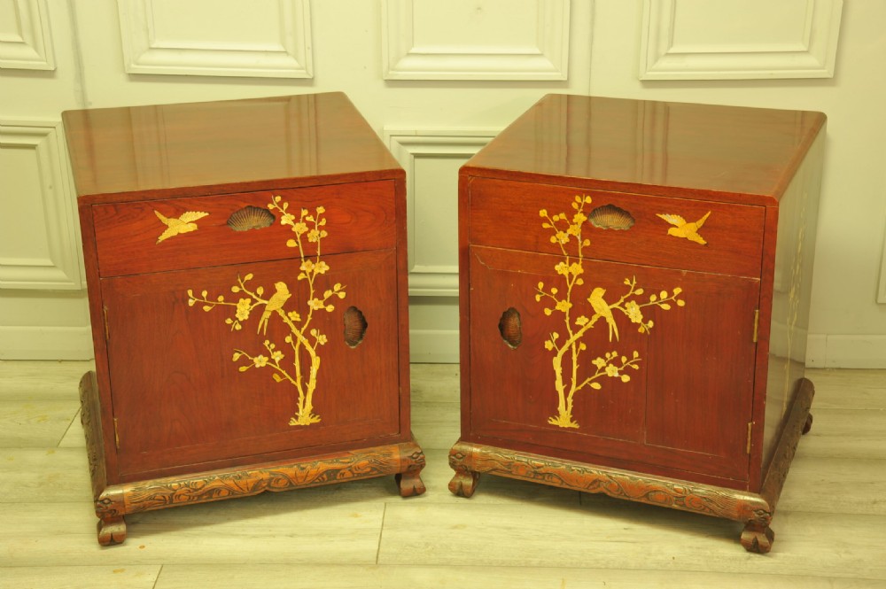 A pair of reddish-brown wood side cabinets featuring hand-painted gilt Chinoiserie floral and bird motifs resting on carved plinths. View X