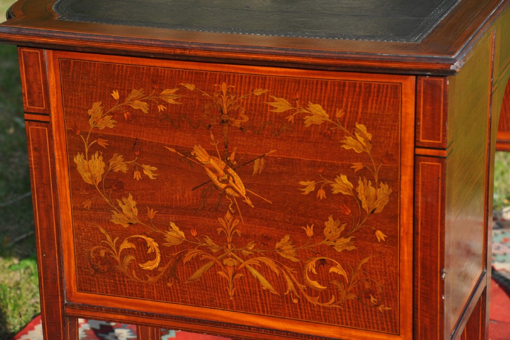 An antique Edwardian inlaid mahogany writing desk featuring a dark leather inset top, seven drawers with brass handles, and floral marquetry side panels. View XIII