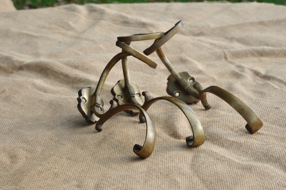 A set of three antique French cast bronze wall-mounted hat and coat hooks with scrolled upper arms and shaped lower pegs. View III
